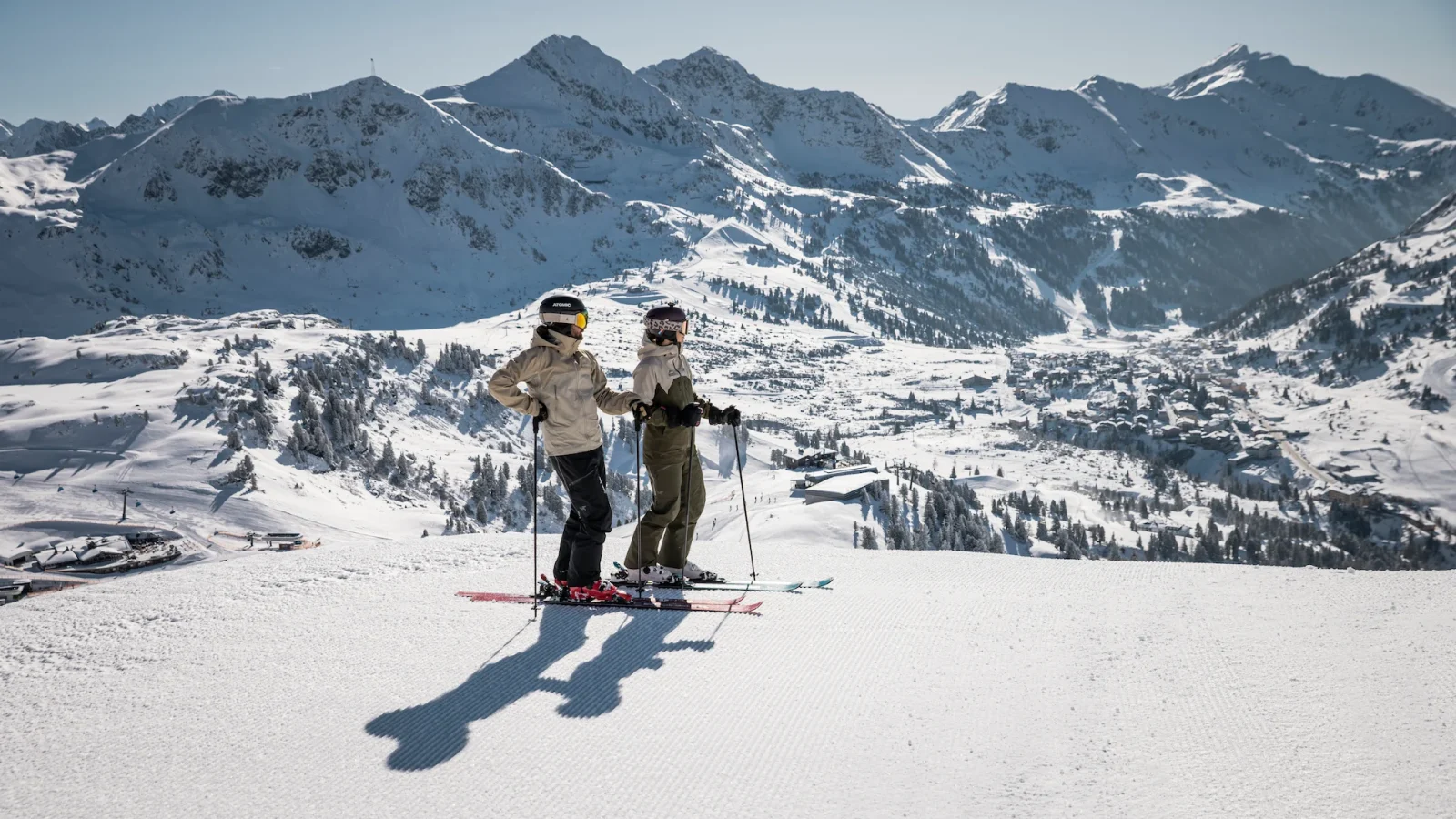 Zwei Skifahrer:Innen genießen das winterliche Bergpanorama
